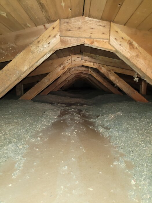 Vind med träbalkar och ett golv av boardskivor omgivet av lösullsisolering.
