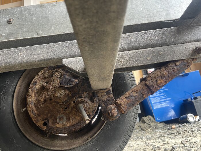 Rostig del av släpvagns underrede och hjul, potentiell renoveringsdetalj och besiktningsfråga.