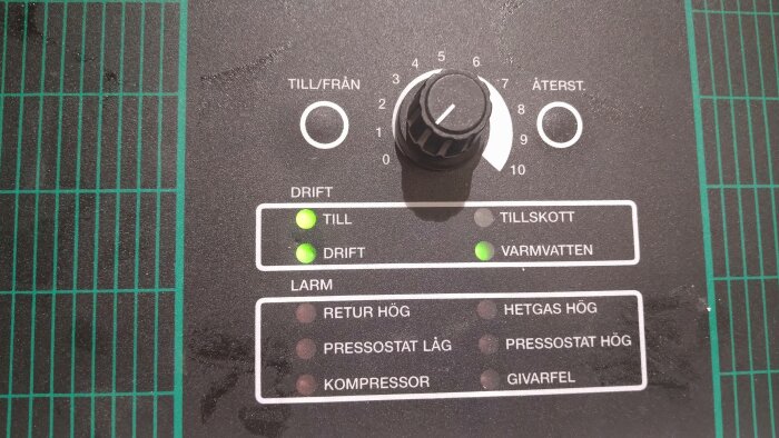 Kontrollpanel på värmepump med inställningar för drift, tillskott och varmvatten. Grön lampa lyser för drift och varmvatten.