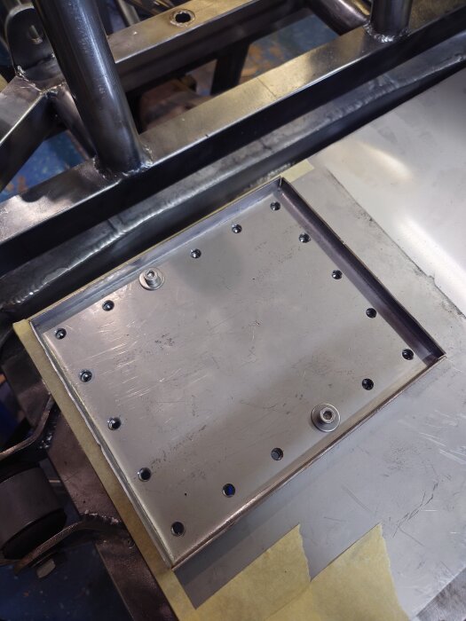 En metallplatta med insexskruvar fastsatt på en ram av metallrör.