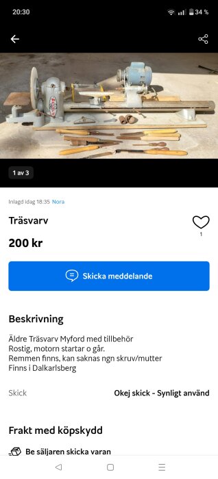 Äldre träskriv med tillbehör på betonggolv. Verktyg med träskaft ligger framför, maskinen delvis rostig.