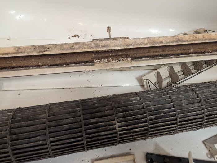 Närbild på en smutsig luftkonditioneringsenhet med damm och smuts ansamlad på dess komponenter.