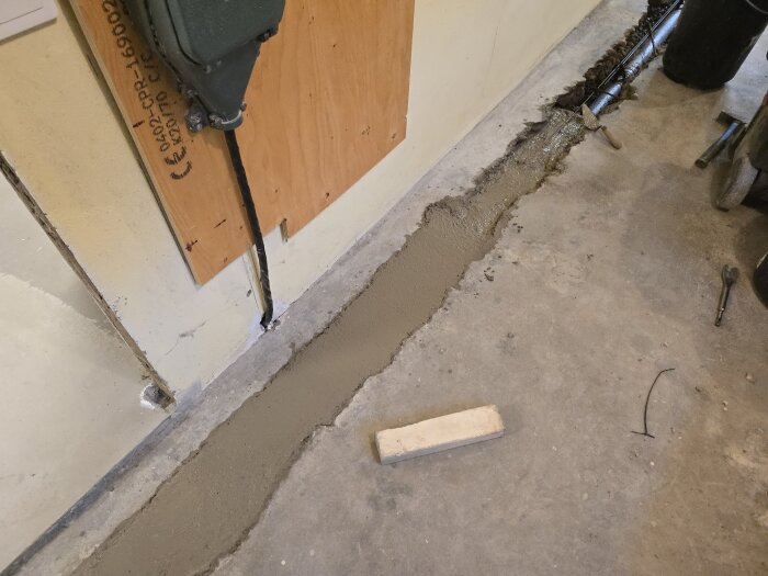Betongränna i hobbyrum under gjutning, halvfylld med betong. Verktyg och byggmaterial synliga på golvet.