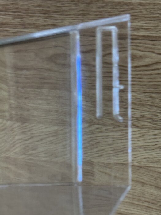 Trasigt hyllfäste till kylskåpsdörr, nära bild på plastkonsol med krokform.