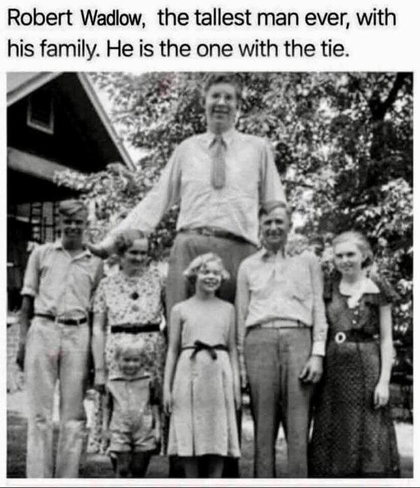 Familjefoto utomhus med en man i slips, betydligt längre än de andra familjemedlemmarna, som står bredvid honom.