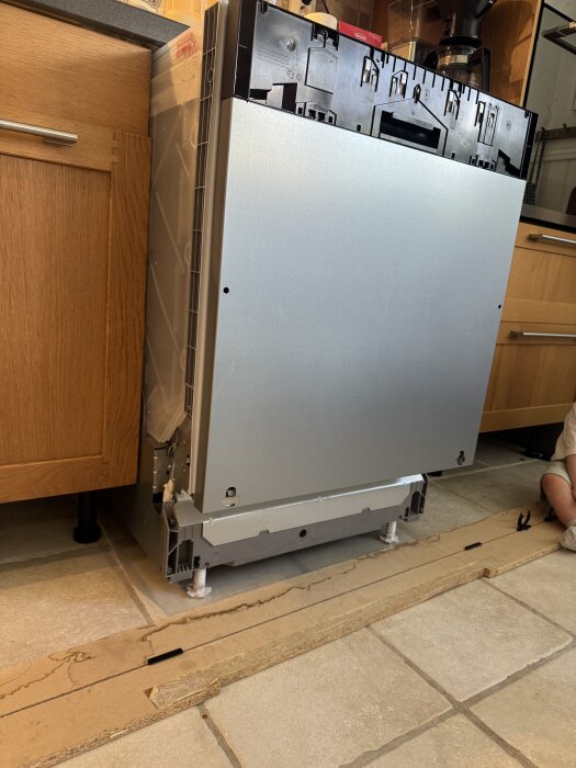 Inbyggd Bosch diskmaskin under installation i kök, med luckan uppfälld och platsen för fjädern synlig, monterad mellan trämöbler.