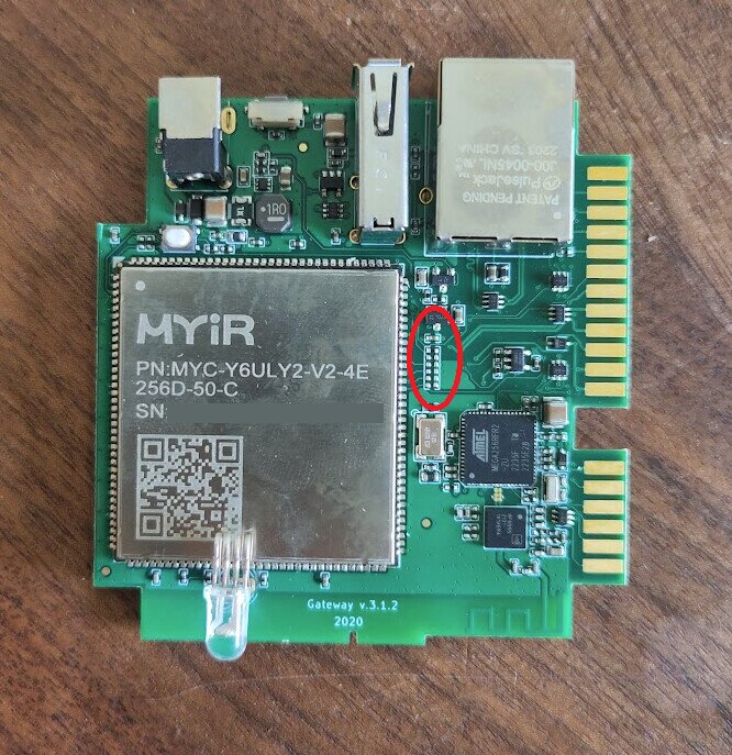 Kretskort med komponenter, ett chip märkt "MYiR" och en markerad pin-header på träbord.