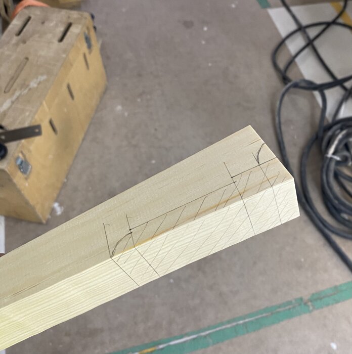 Träbit med markerade linjer för sågning, verktygslåda i bakgrunden.