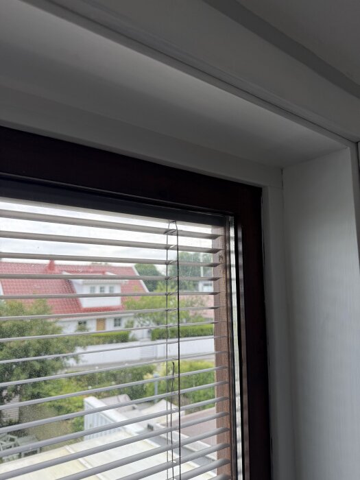 Persienn med ett brustet snöre vid ett fönster, vilket orsakar problem med dess funktion.