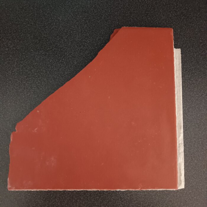 Tegelröd matt klinkerplatta med dimensionerna 19x19 cm och en avfasad kant, som visas ovanpå en mörk yta.