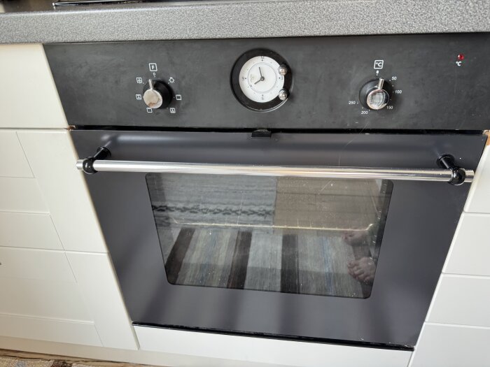 Svartvit ugn med två vred och en urtavla för inställning; fokus på bortkoppling av klockans relä kopplat till ugnens funktion.