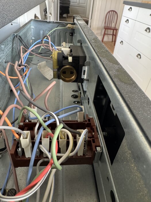 Inuti en ugn med synliga färgade kopplingskablar och komponenter som styr klockan eller urverket.