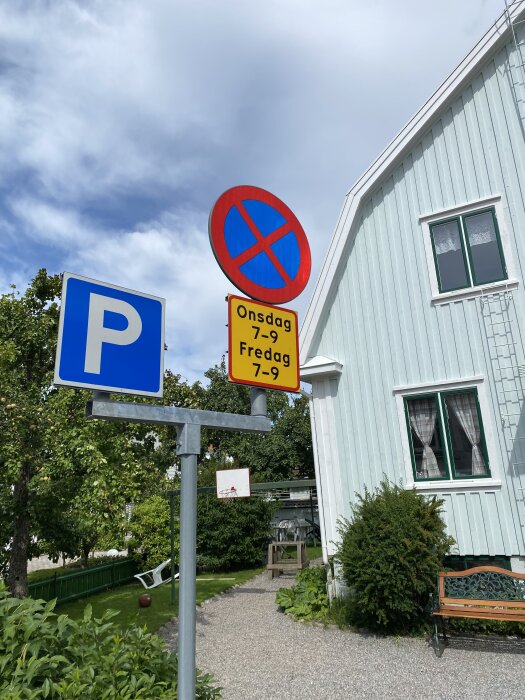 Två motstridiga trafikskyltar: en blå parkskylt och en röd-blå förbudsskylt med tider onsdag 7-9 och fredag 7-9, bredvid ett hus.
