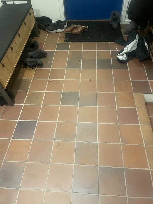 Klinkergolv med varierande färg, troligen äldre Höganäs, omgivet av skor och bänk.