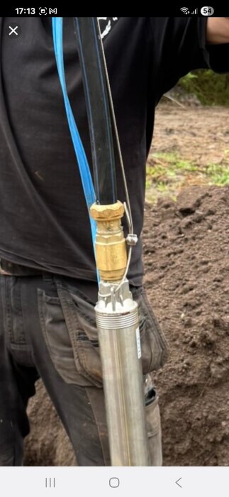 Pumpdel med koppling och sladd synlig, mannen i bakgrunden håller i den.