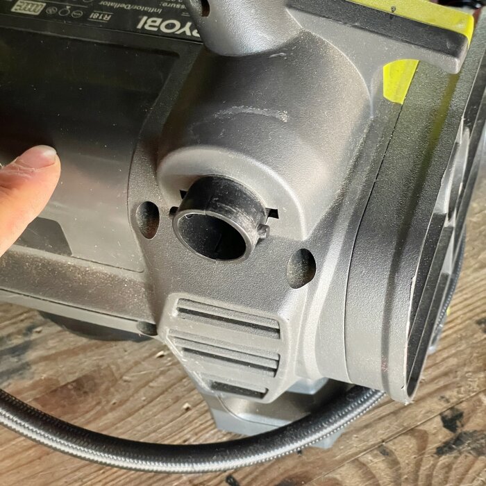 Närbild av slanganslutningen på en Ryobi-kompressor, modell R18I, med en hand som pekar mot anslutningen.