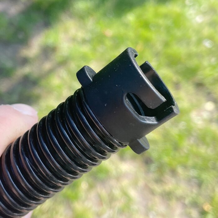 Svart räfflad adapter eller slangände för Ryobi-kompressor R18I visas mot en grön bakgrund.