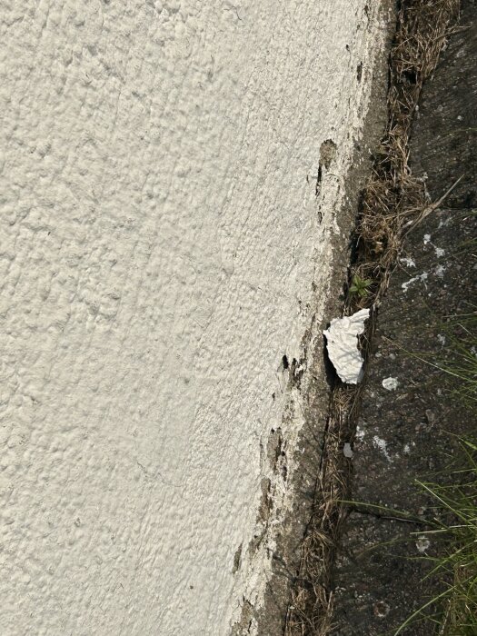 Flagnande färg på en putsad mur med synliga skador och bitar av färg som lossnat.