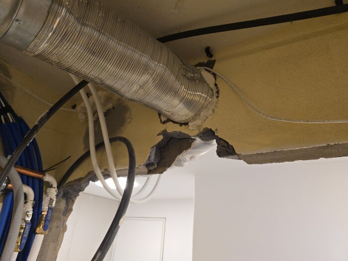 Riven vägg med synligt ventilationsrör och elkablar mot gul bakgrund.