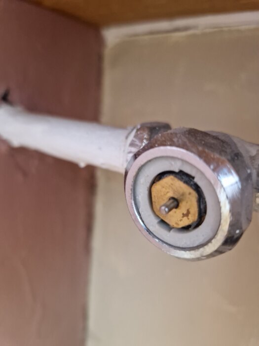 Närbild av radiatoranslutning utan termostat, med en synlig ventilspindel i metall.