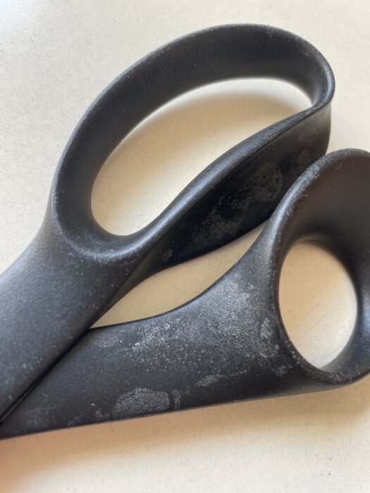 Svarta handtag med vita beläggningar på ytan, möjligen efter diskmedelsanvändning, på plastmaterial.