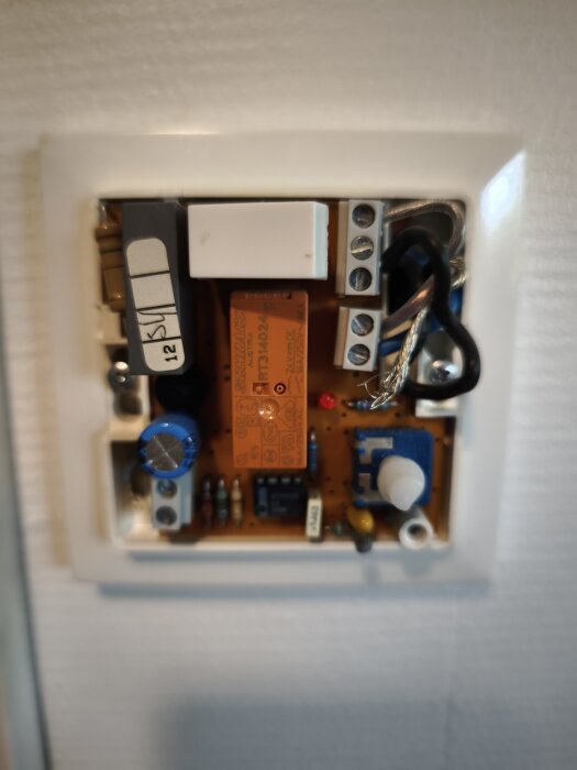 Elektronisk krets med komponenter som reläer och kondensatorer monterade i en väggpanel.