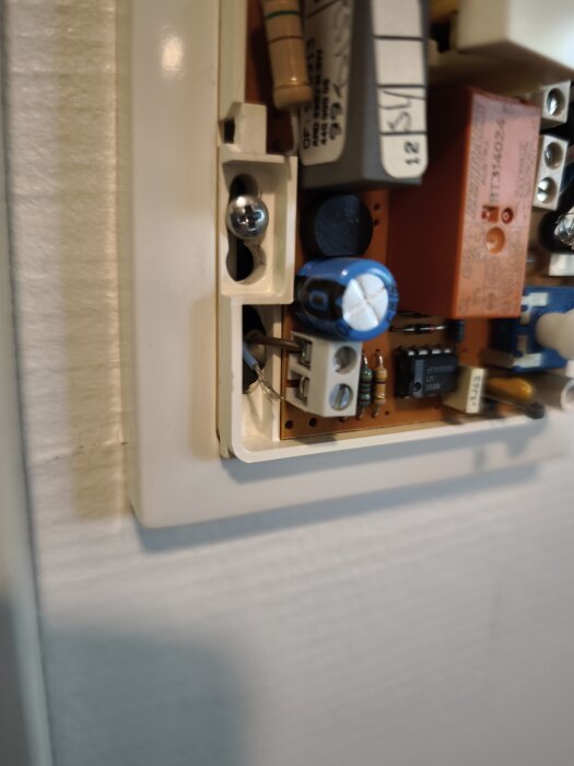 Inre del av elektrisk panel med synligt anslutna kablar och komponenter, inklusive kondensatorer och kretskort.