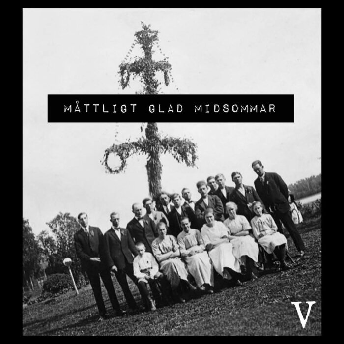 Gruppfoto av människor framför en midsommarstång med texten "Måttligt glad midsommar".  Bilden är i svartvitt.
