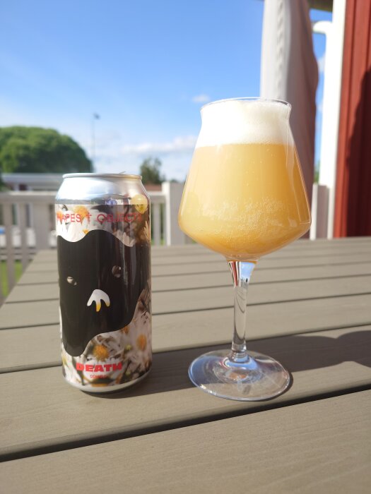 En ölburk med etiketten "Death" från Shapes & Objects bredvid ett glas öl på ett bord i solen.