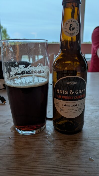 Flaska och glas med "Innis & Gunn Islay Whisky Cask Beer" på träbord, del av avslappnad belöning efter paddling.