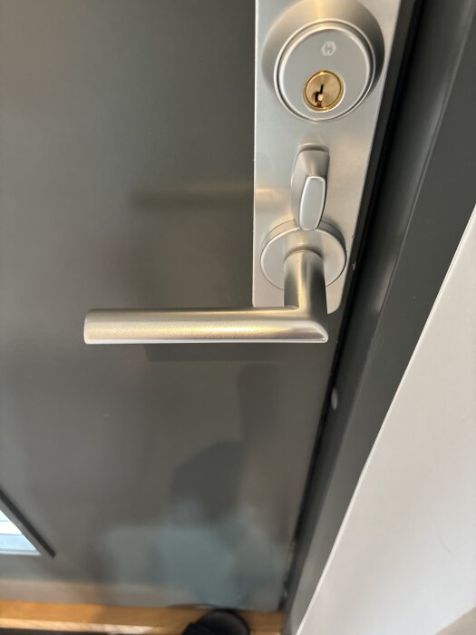 Dörrhandtag med låsmekanism och nyckelhål överst, fråga om hur det låses.