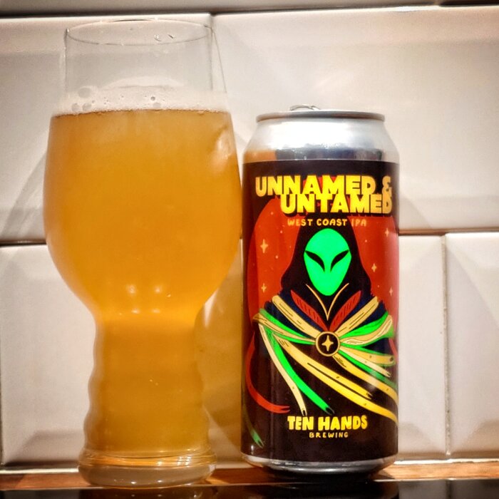 En burk av Ten Hands Brewing's "Unnamed & Untamed" West Coast IPA och ett glas med gyllene öl på kaklat underlag.