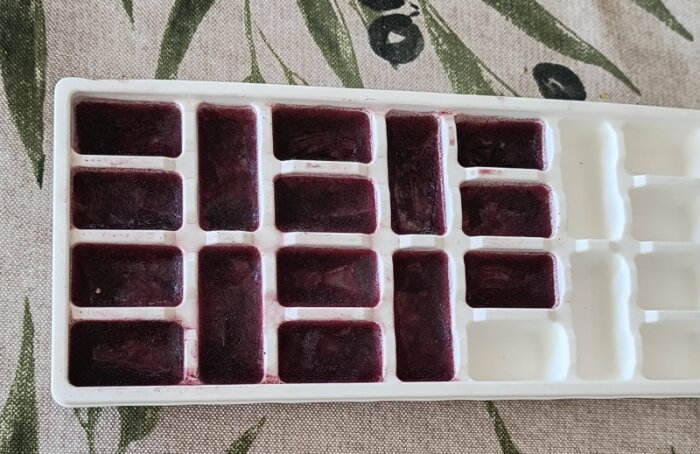 Isbitsform med frysta kuber av rödvin.