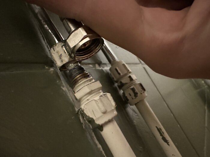 Hand kopplar en ny badrumskranledning till befintliga vattenrör, med fokus på olikheter i storlek och behovet av en adapter för anslutning.