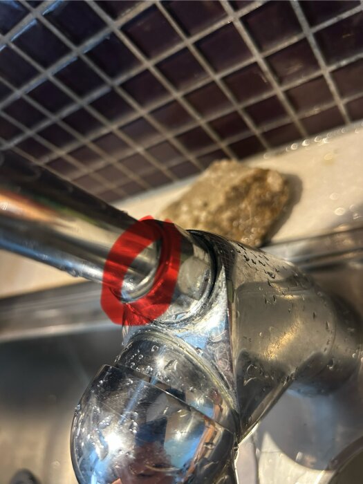 Närbild på kromblandare med läcka ovan O-ring, omgiven av rödfärgad markering. Kaklad bakgrund synlig.