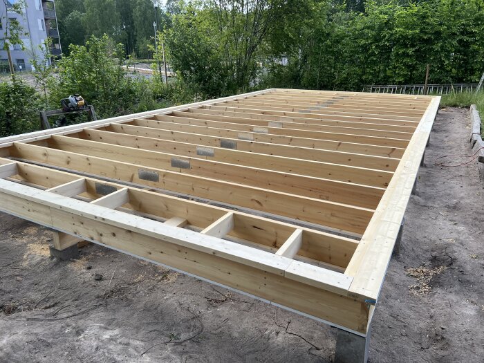 Träbjälklag byggt på en grund utomhus med omgivande grönska. Snart dags för arbete på högre nivå.