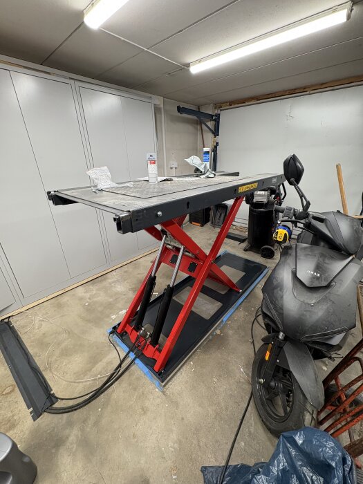 Lyftanordning utan smörjnipplar i garage med motorcykel bredvid.