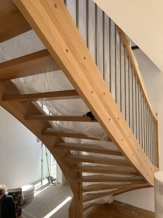 Trätrappa med oljad yta och mattsken, skyddad med plast för renovering, användning av Osmo hårdvaxolja nämns i texten.