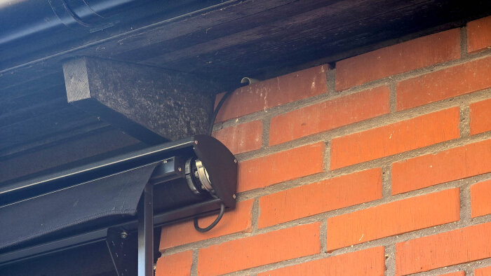 Motorkabel och VP-rör genom tegelvägg under takfotsbräda med rullad markis.