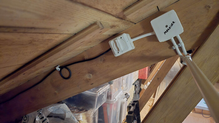 Elektrisk installation på vinden med kablar och en vit brytare monterade på en sned takstol, med märkning "MARKISER" på en kopplingsdosa.