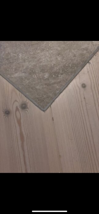 Trägolv möter klinkerplattor i en hörna, med liten fog mellan materialen.