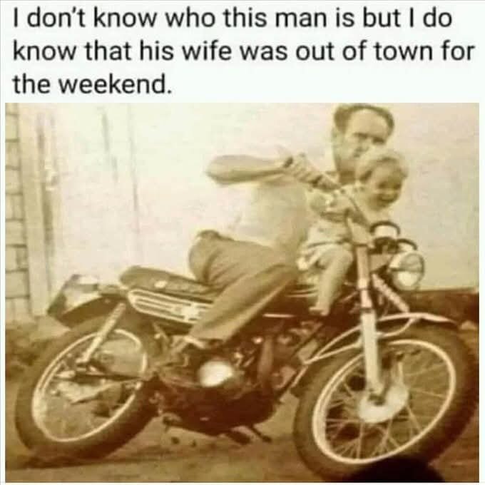 En äldre bild av en man som sitter på en motorcykel tillsammans med ett skrattande barn.