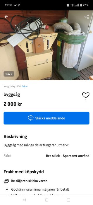 Byggsåg med beige och grönt hölje, sladdar ovanpå, och ett dammuppsamlingssystem intill, står på ett trädäck vid en röd vägg.