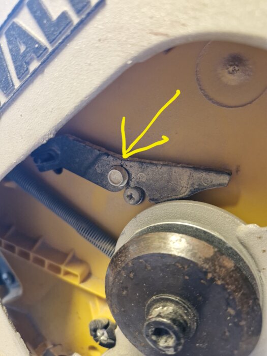 Närbild av en trasig hävarm på en Dewalt DW707 kap- och gersåg med en gul pil som pekar på den skadade delen.