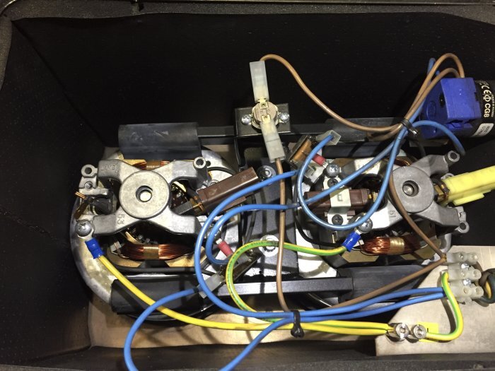 Motorer med kablar och elektronikkomponenter i en dammsugarenhet, synliga spiraler och kopplingar.