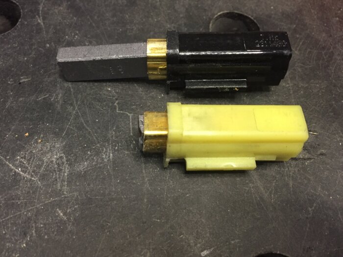 Två utbytbara motorborstar, en i svart hölje och en i gult, ligger på en arbetsbänk, används för att förbättra sugkrafterna i en snickerboa.