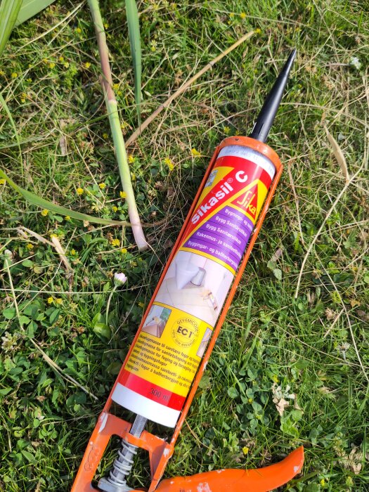 Orange fogpistol med Sikasill C-kassett ligger i gräset.