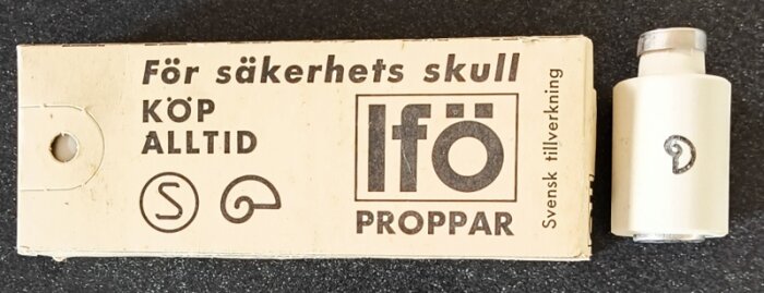 Förpackning och propp från Ifö med historisk design och text: "För säkerhets skull, köp alltid Ifö proppar, svensk tillverkning".