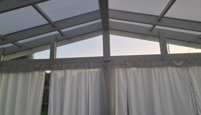 Inglasat uterum med vitt tak och gardiner.