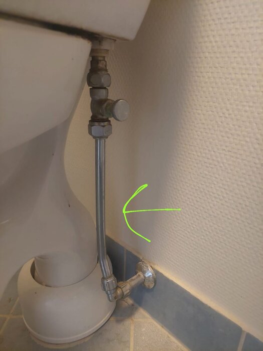 Toalettrör och anslutningar i ett äldre badrum, väggen visar två rör med olika diameter.